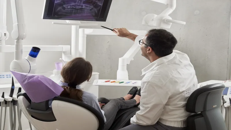 Odontólogo mostrando una radiografía panorámica a su paciente en el consultorio