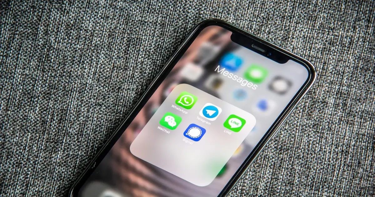 Teléfono con aplicaciones de mensajería representando el envío de comunicados masivos